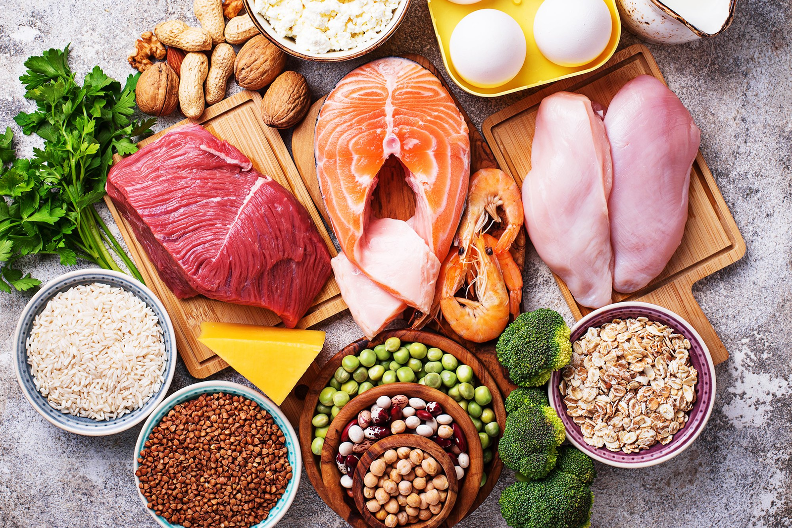 A variety of high-protein, nutrient-dense foods including lean meats, salmon, eggs, nuts, grains, and vegetables, commonly used in a diet to drop fat while promoting muscle growth and overall health.