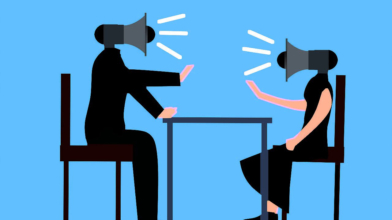 Two silhouetted figures with megaphones for heads sit facing each other at a table.