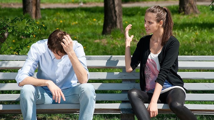 Two people on a park bench, one with head in hand, the other gesturing animatedly.