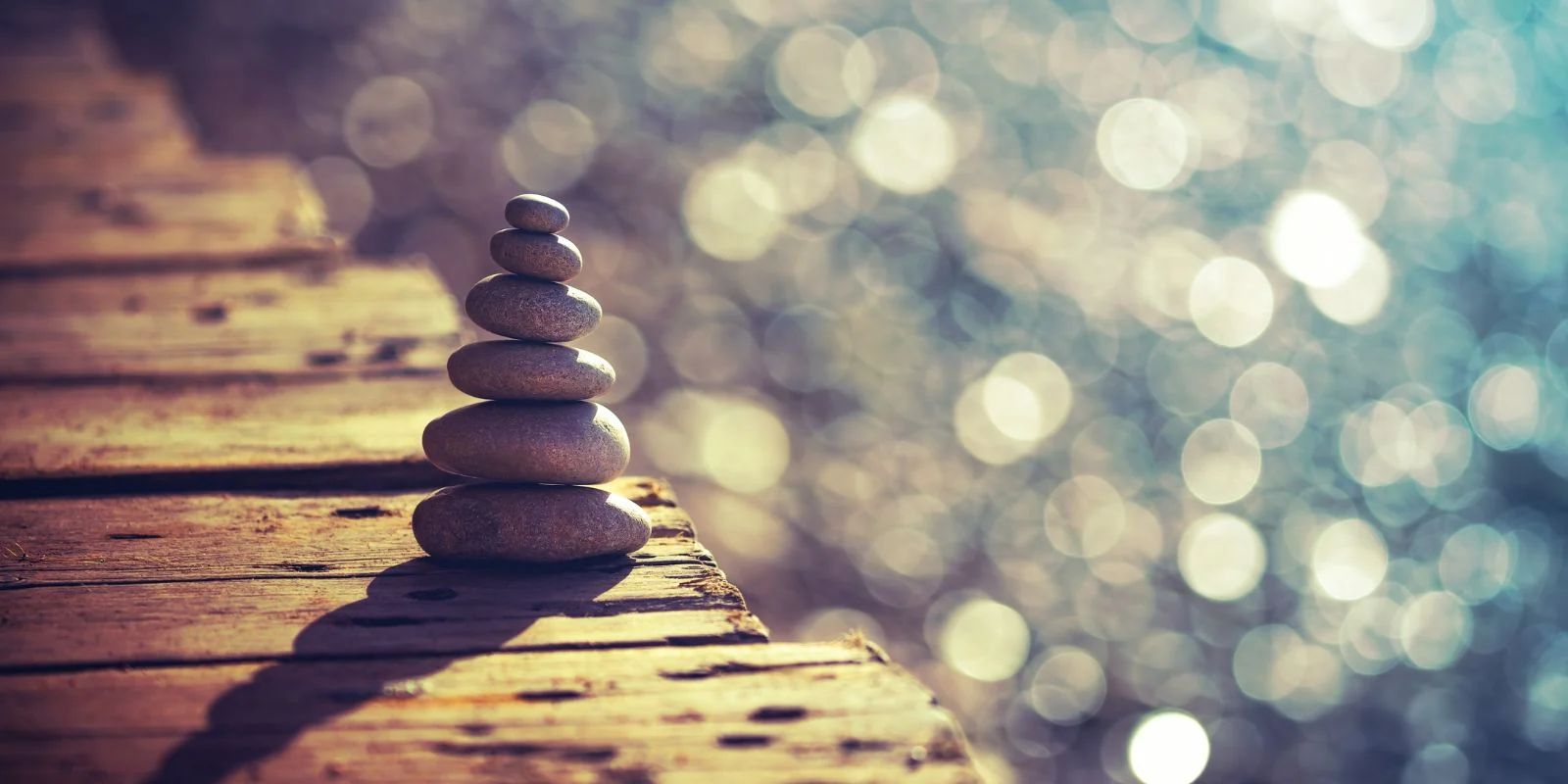 Stack of smooth stones on a wooden surface with bokeh light background.