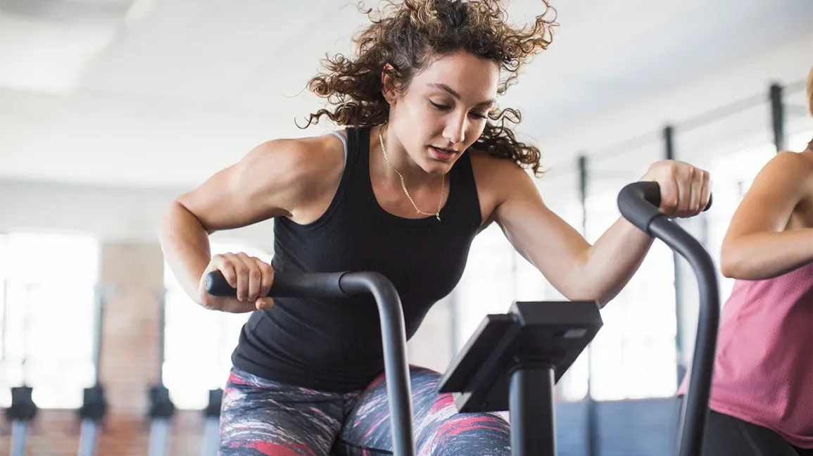 Woman exercising on an elliptical trainer at a gym.