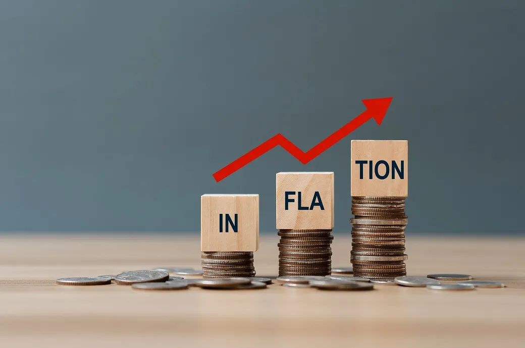 Three stacks of coins with blocks spelling "INFLATION" and an upward arrow graph.