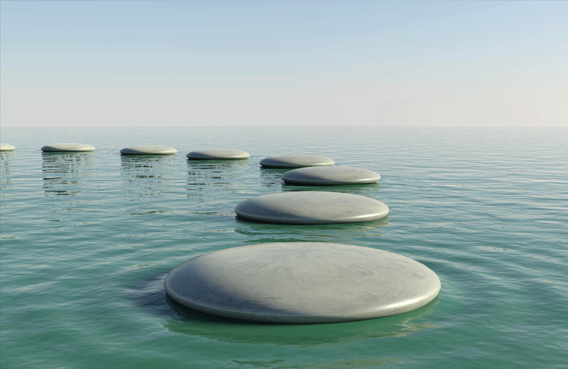 Round stepping stones arranged in water with a clear sky backdrop.